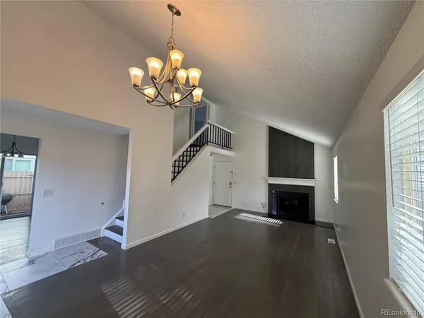 a view of a livingroom with a fireplace a chandelier and windows