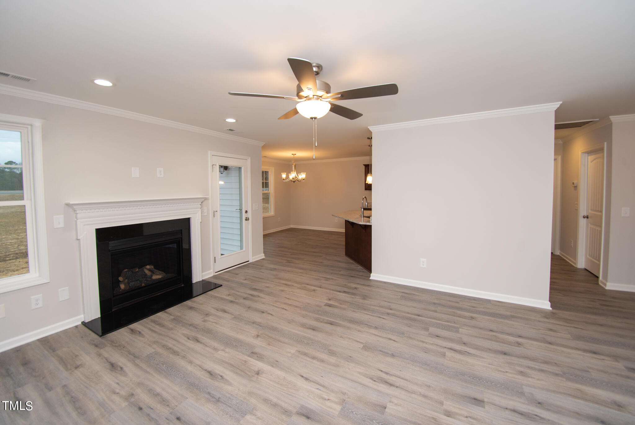 243 Waters Edge Drive Erwin, NC 28339 - Photo 6 of 53 an empty room with wooden floor a ceiling fan a fireplace and windows