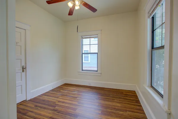 a view of empty room with wooden floor and fan