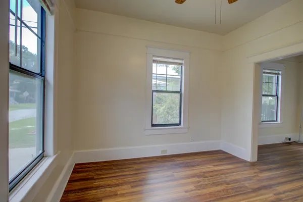 a view of an empty room with wooden floor and a window