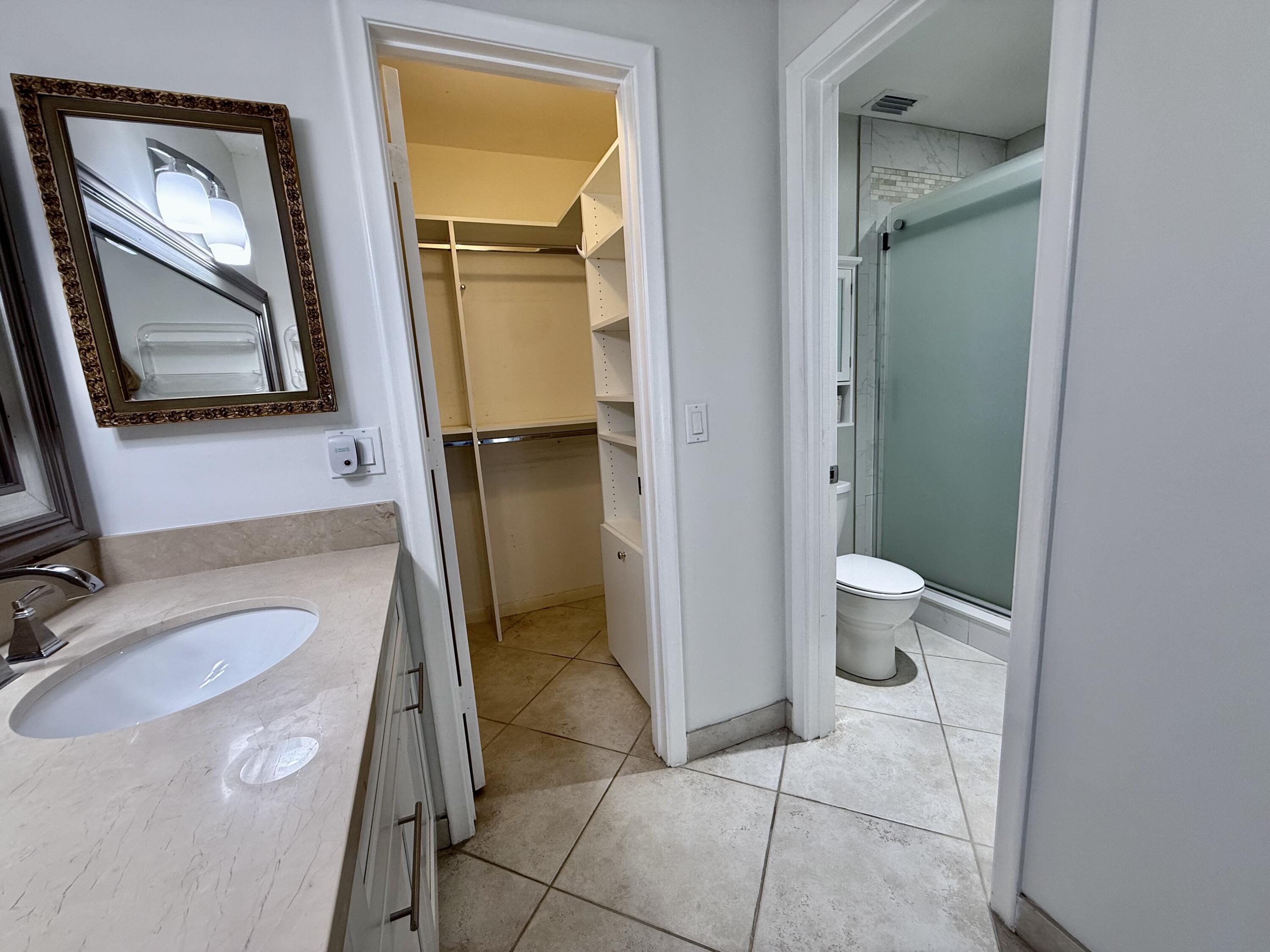 1720 Northwest 20th Avenue, Unit 204 Delray Beach, FL 33445 - Photo 18 of 30 a bathroom with a granite countertop sink a mirror and a toilet
