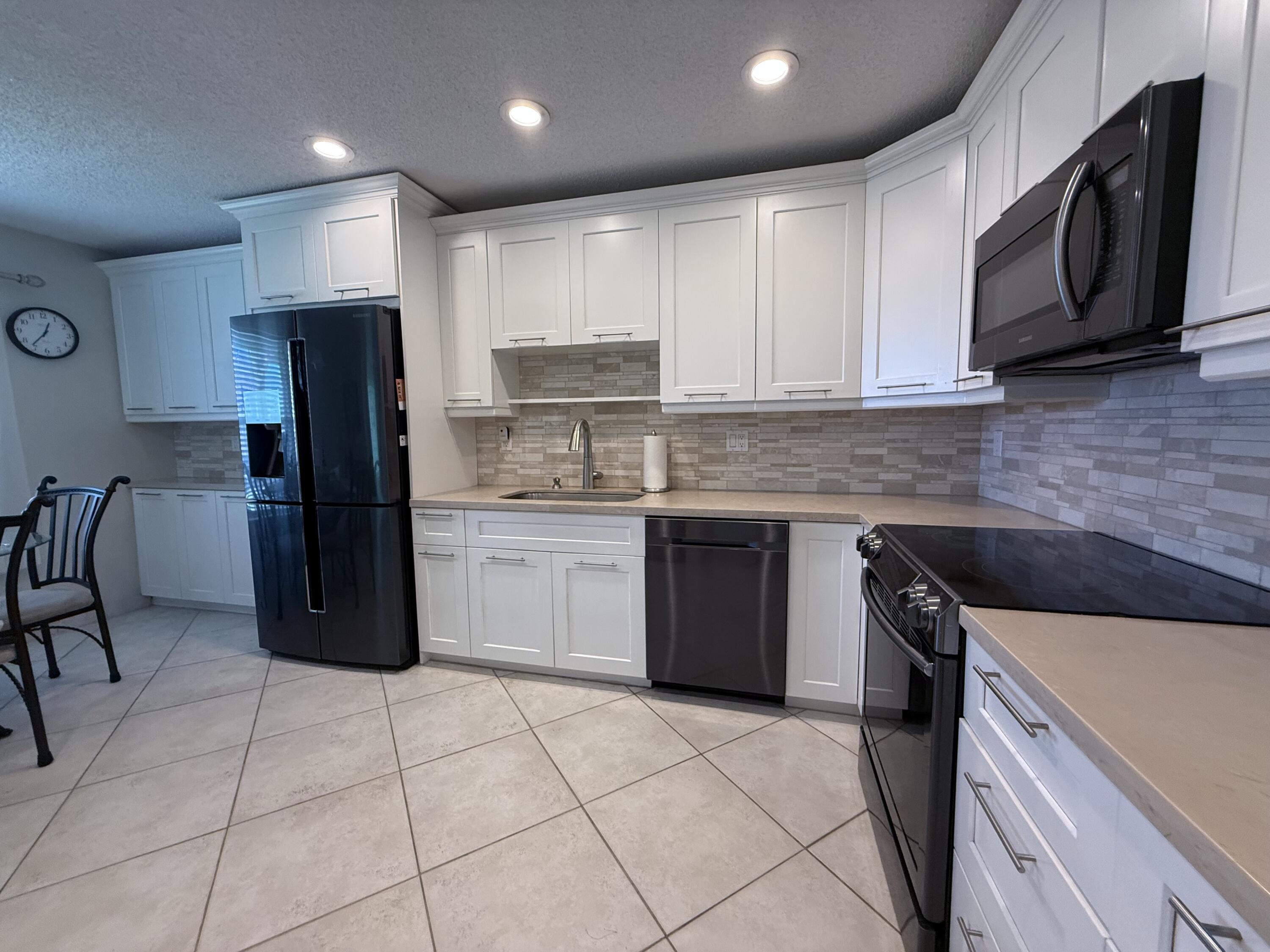 1720 Northwest 20th Avenue, Unit 204 Delray Beach, FL 33445 - Photo 10 of 30 a kitchen with stainless steel appliances granite countertop a refrigerator sink and cabinets
