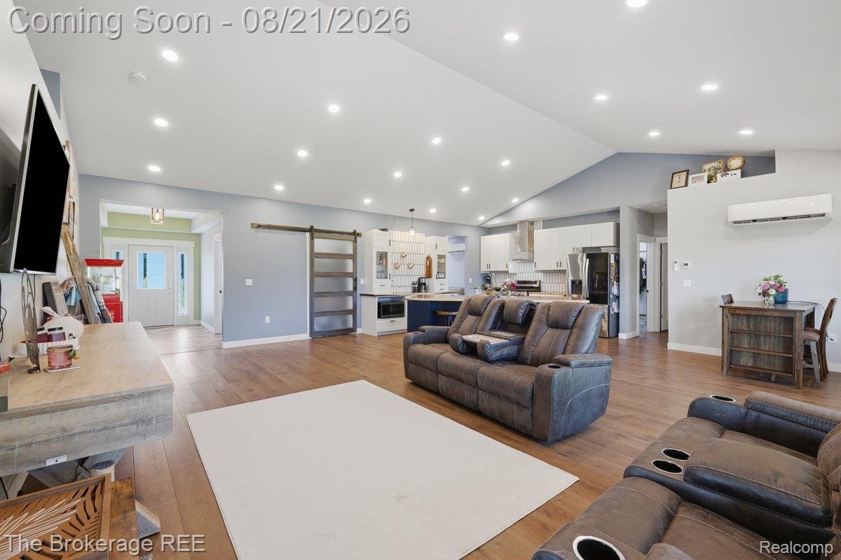 9161 East Coldwater Road Davison, MI 48423 - Photo 4 of 52 Vaulted ceilings with recessed lighting, wood-finish flooring, kitchen with white cabinetry and stainless steel appliances, and a barn door accent
