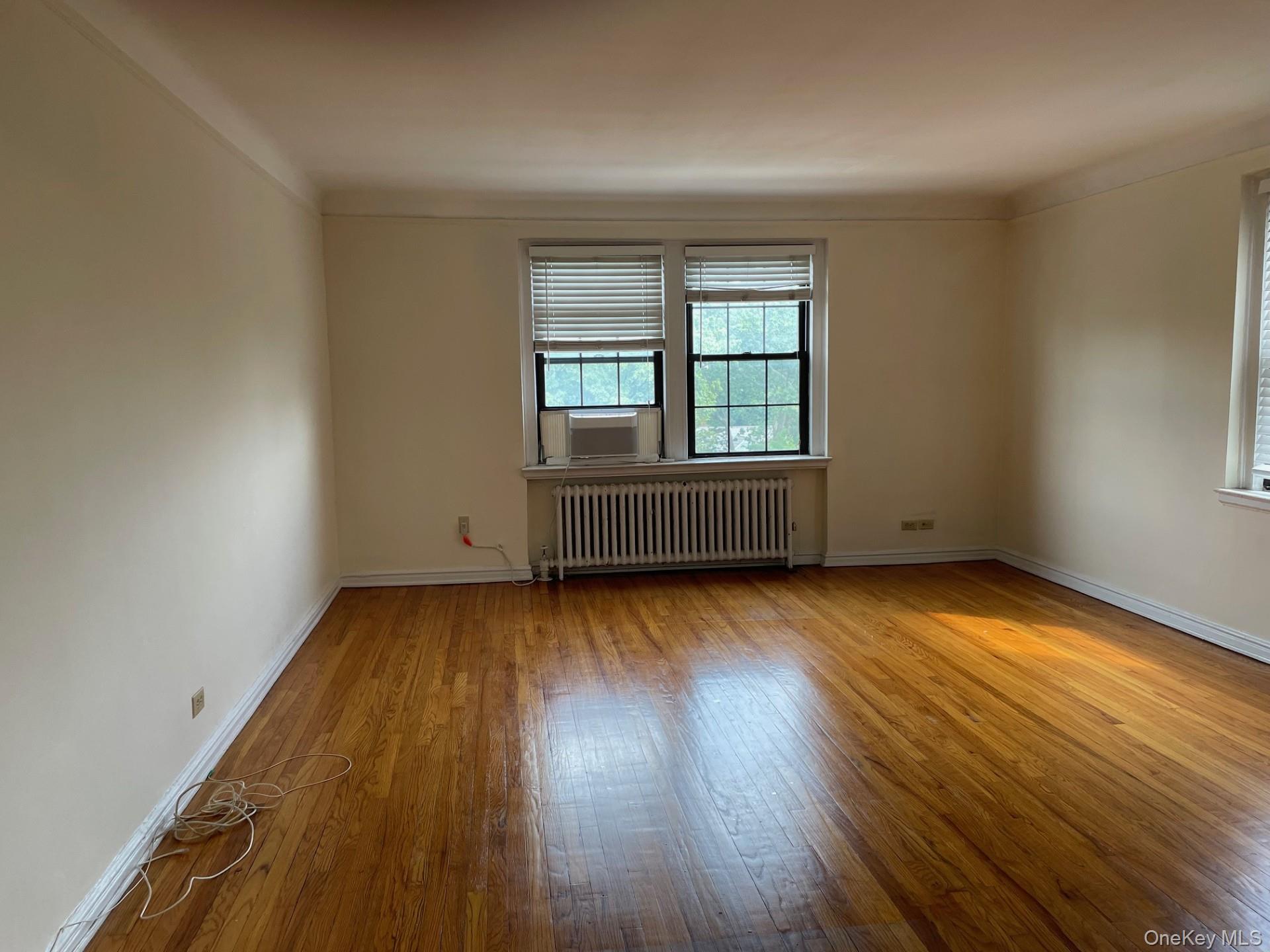 192 Garth Road, Unit 4N Scarsdale, NY 10583 - Photo 12 of 32 an empty room with wooden floor and windows