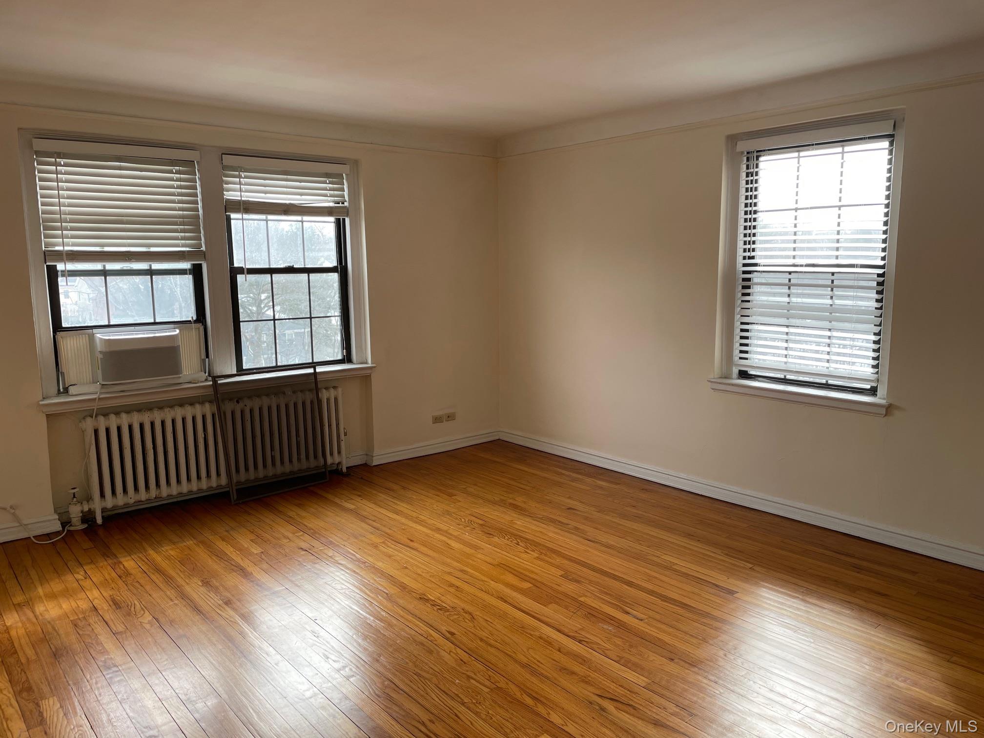 192 Garth Road, Unit 4N Scarsdale, NY 10583 - Photo 13 of 32 an empty room with wooden floor and windows