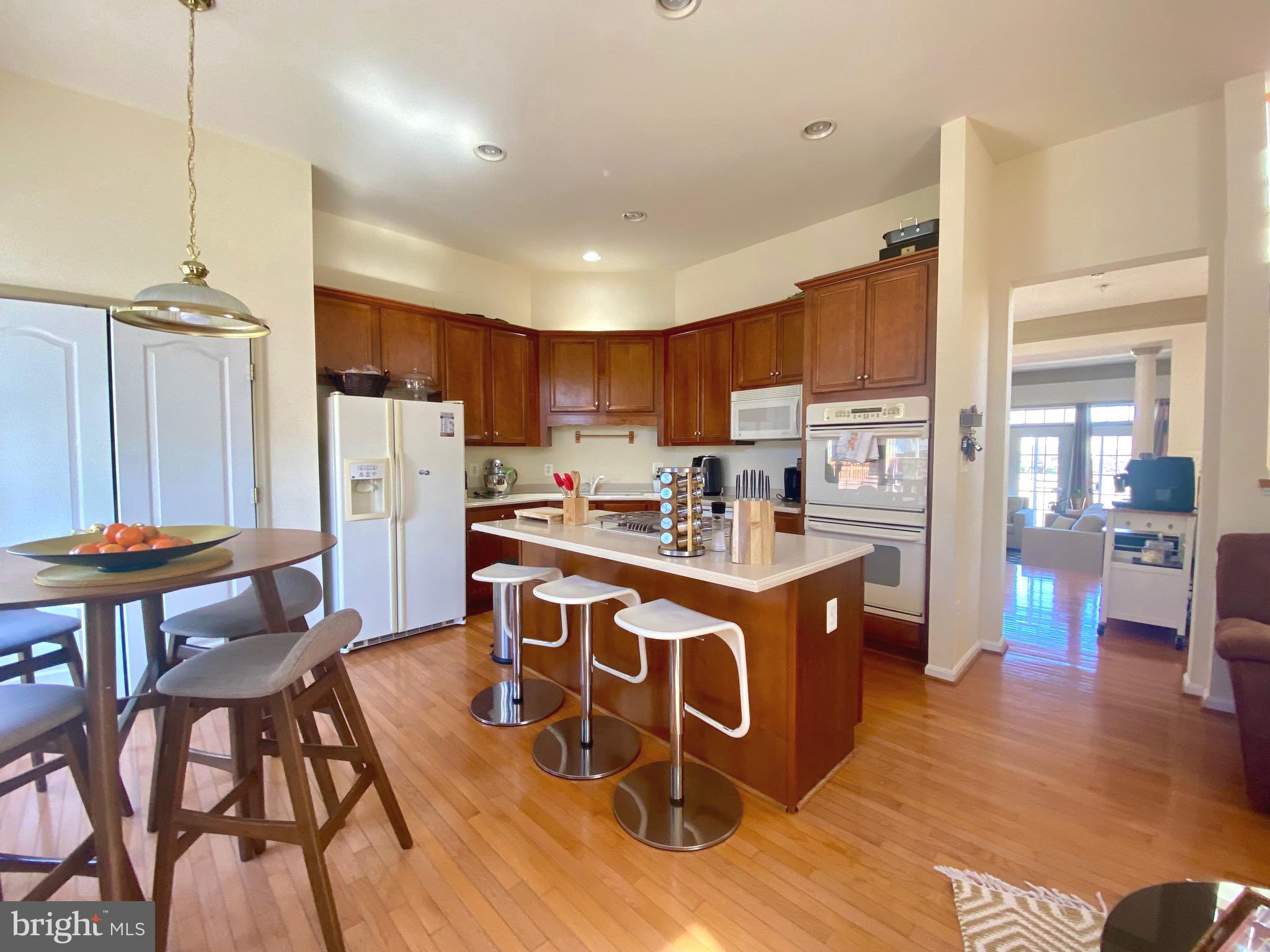 21975 Windover Drive Broadlands, VA 20148 - Photo 8 of 37 a kitchen with stainless steel appliances granite countertop a stove top oven a refrigerator a sink and a dining table with wooden floor