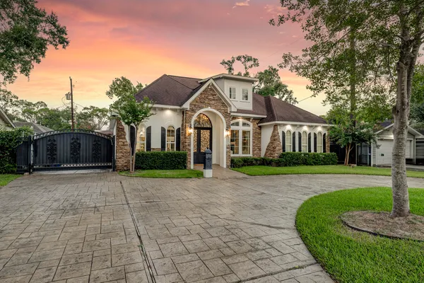a front view of a house with a garden and trees
