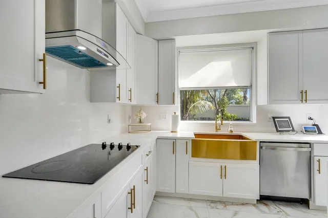 a kitchen with stainless steel appliances a stove a sink a chimney and a large window