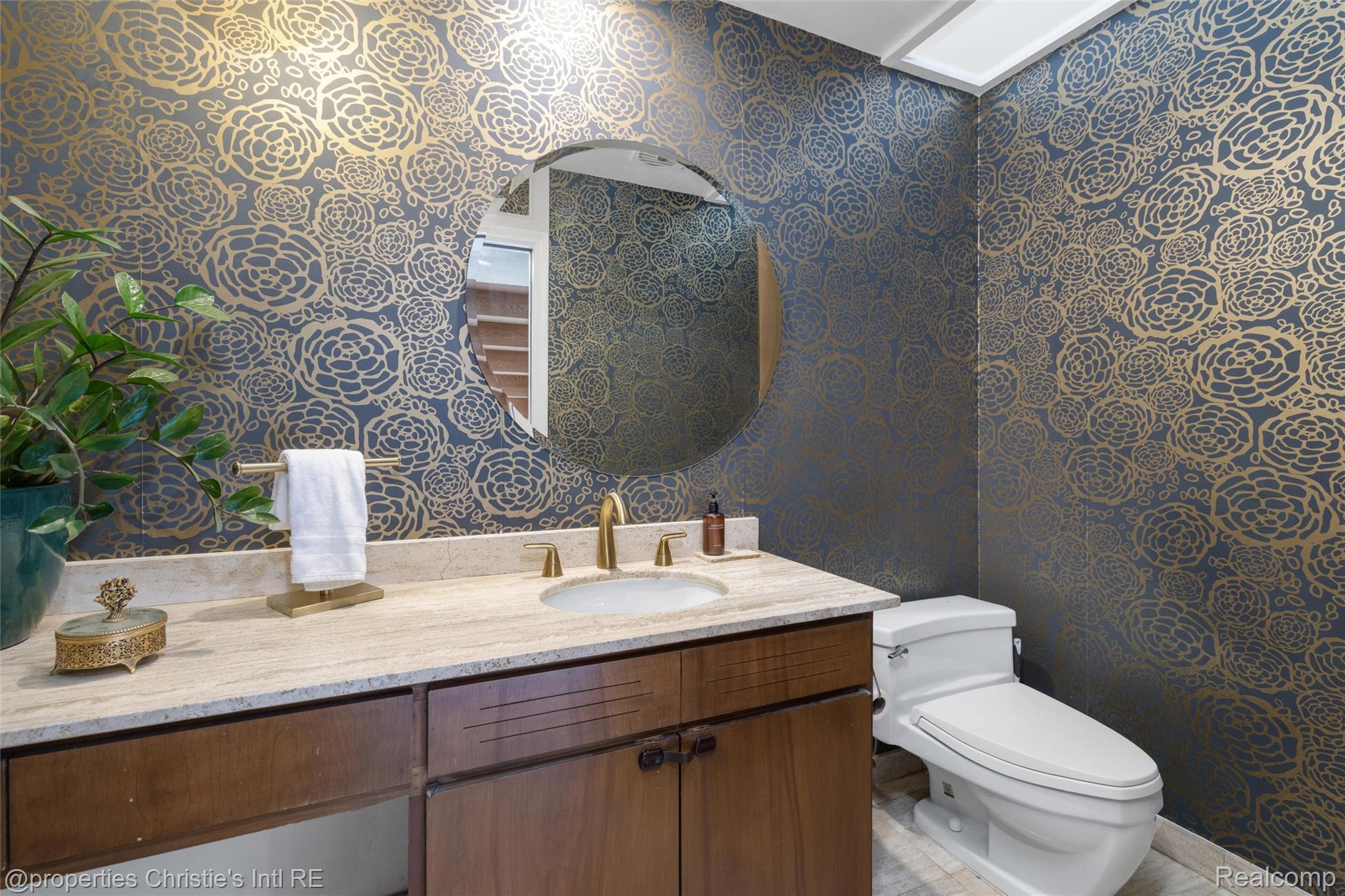 2771 West Seven Mile Road Detroit, MI 48221 - Photo 34 of 57 Powder room featuring botanical-patterned accent wallpaper, a wood-finish vanity with a stone countertop, a circular mirror, and a modern toilet