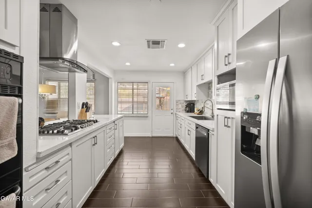 a large kitchen with stainless steel appliances granite countertop a stove a sink dishwasher and a refrigerator