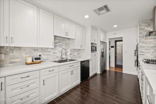 a kitchen with granite countertop white cabinets and stainless steel appliances