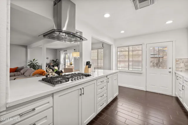 a kitchen with a sink dishwasher and white cabinets with wooden floor