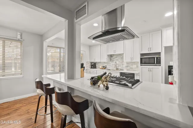 a kitchen with stainless steel appliances granite countertop a sink a stove a refrigerator cabinets and dining table