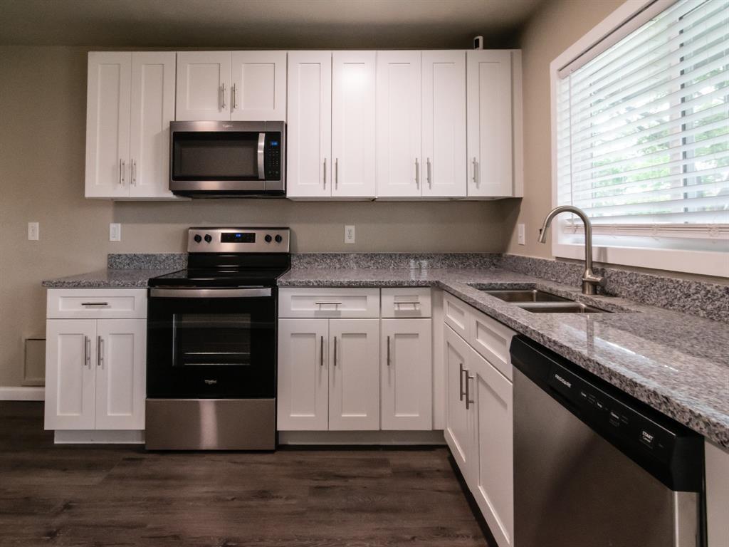 3125 Abbey Road Carrollton, TX 75007 - Photo 1 of 1 a kitchen with stainless steel appliances granite countertop a stove a sink dishwasher and a microwave oven with wooden cabinets