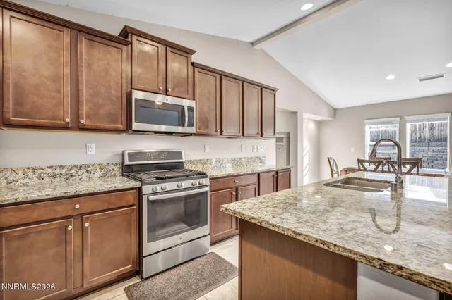 a kitchen with granite countertop a stove sink and microwave