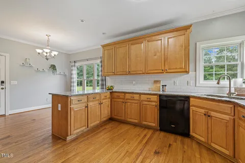a kitchen with stainless steel appliances granite countertop wooden cabinets a stove a sink and dishwasher with wooden floor