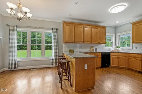 a kitchen with stainless steel appliances granite countertop a stove a sink dishwasher and a refrigerator with wooden floor