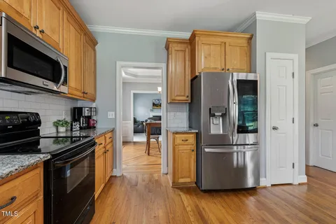 a kitchen with stainless steel appliances granite countertop a refrigerator a stove top oven a sink and dishwasher with wooden floor