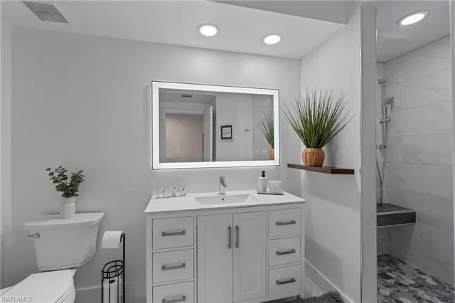 a bathroom with a granite countertop sink vanity mirror and toilet