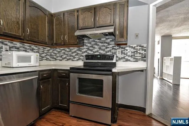 a kitchen with granite countertop wooden cabinets and a stove top oven