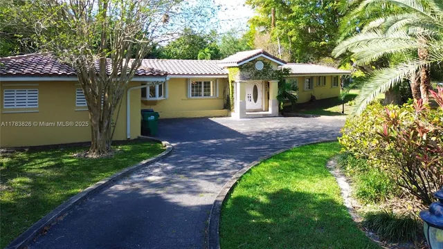 a front view of a house with a garden and tree
