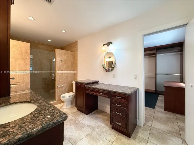 a spacious bathroom with a granite countertop sink a mirror and a shower