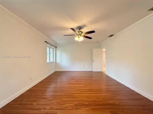 a view of an empty room with window and wooden floor