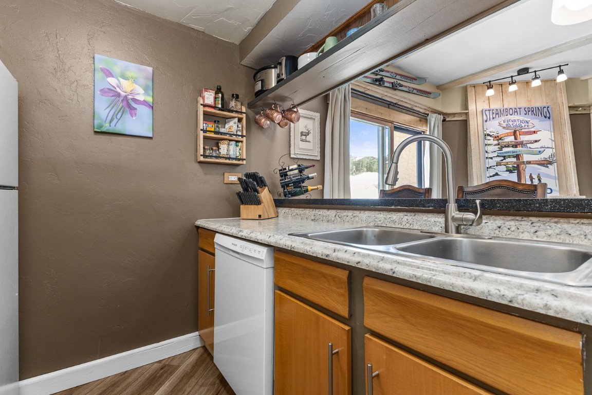 1945 Cornice Road, Unit 101D Steamboat Springs, CO 80487 - Photo 6 of 33 Kitchen featuring dishwasher, light countertops, a textured wall, wood finished floors, and a sink