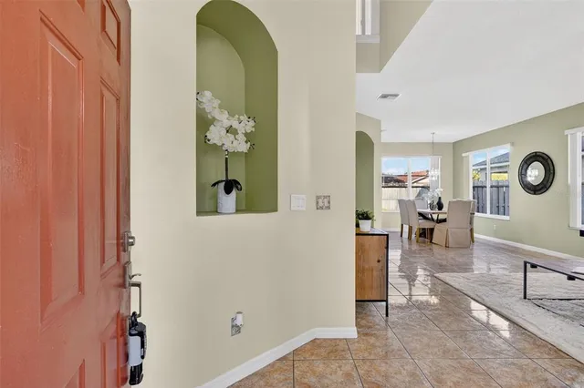 a living room with furniture and a dining table next to a window