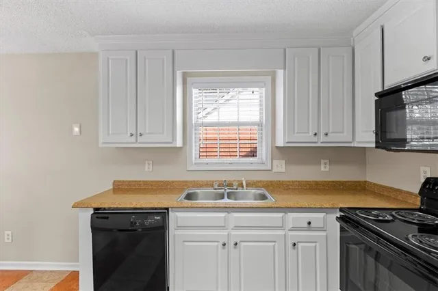 a kitchen with stainless steel appliances granite countertop white cabinets and a stove top oven