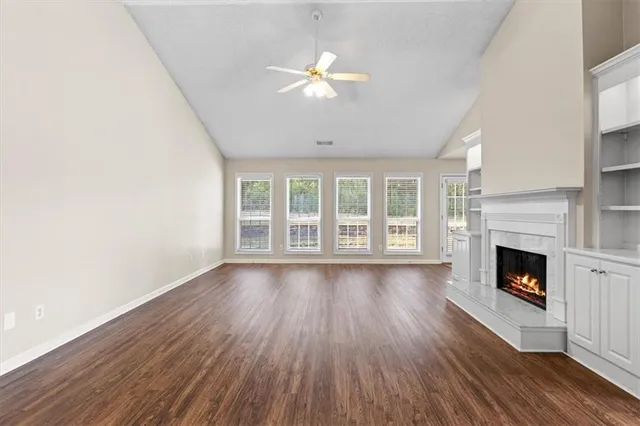 a view of an empty room with wooden floor fireplace and a window