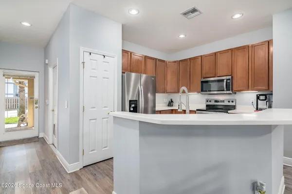 a kitchen with stainless steel appliances granite countertop a refrigerator a stove top oven a sink and dishwasher with wooden floor