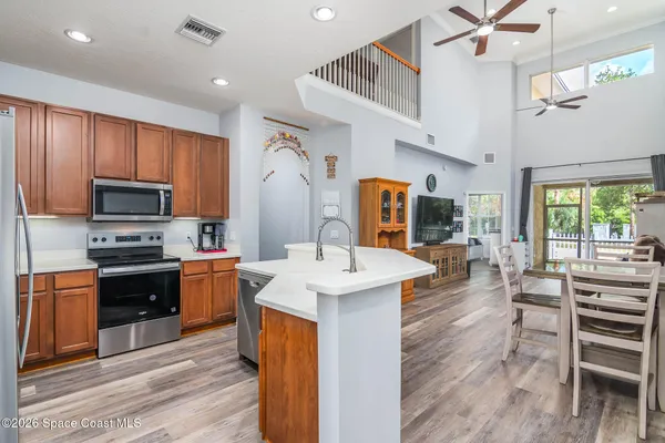 a kitchen with stainless steel appliances kitchen island granite countertop a sink dishwasher a stove and a refrigerator with wooden floor