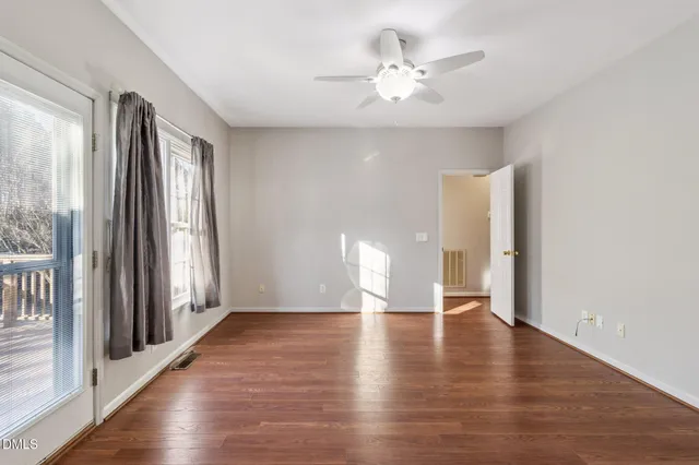 a view of an empty room with window and wooden floor