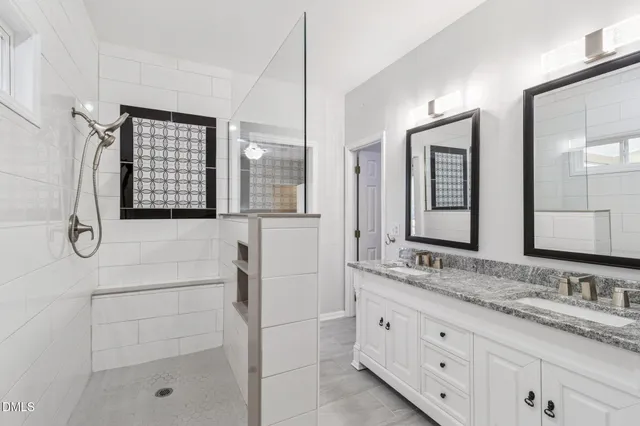 a bathroom with a granite countertop sink two mirror and shower