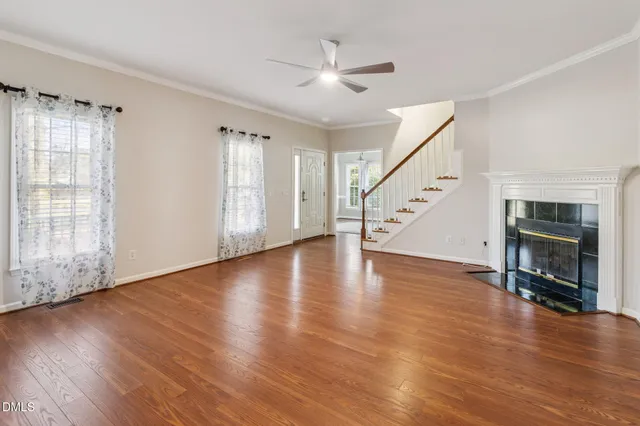 a view of an empty room with wooden floor fireplace and a window
