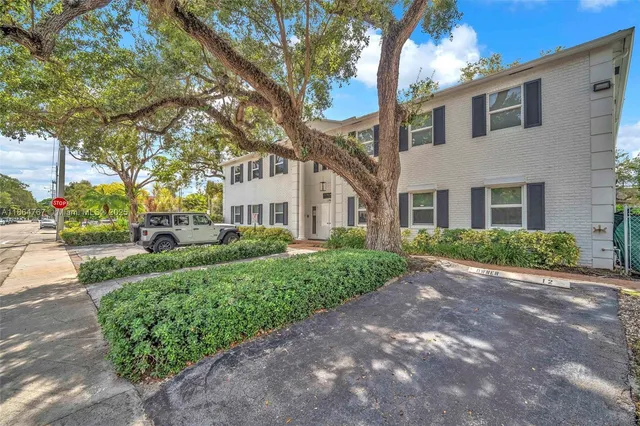 a view of a white house next to a road and yard
