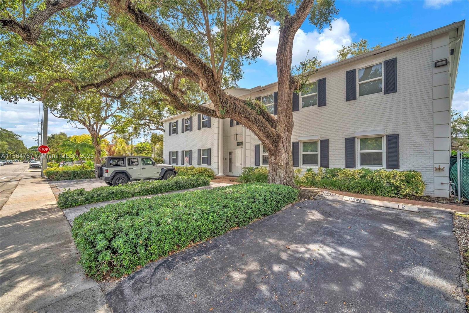 a view of a white house next to a road and yard