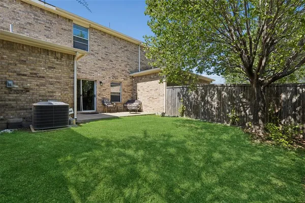 a view of a backyard with brick wall and a large tree