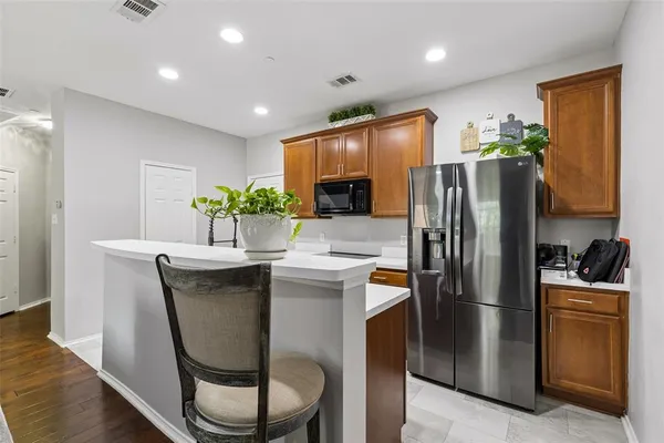 a kitchen with stainless steel appliances granite countertop a refrigerator a stove a sink a microwave a dining table and chairs with wooden floor