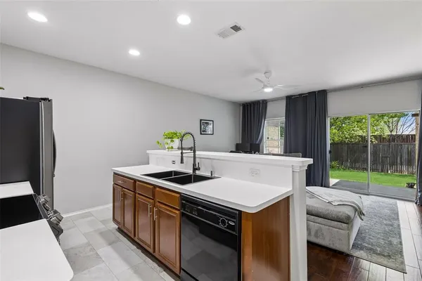 a kitchen filled with stainless steel appliances granite countertop a sink a stove a refrigerator a washer and dryer with wooden floor