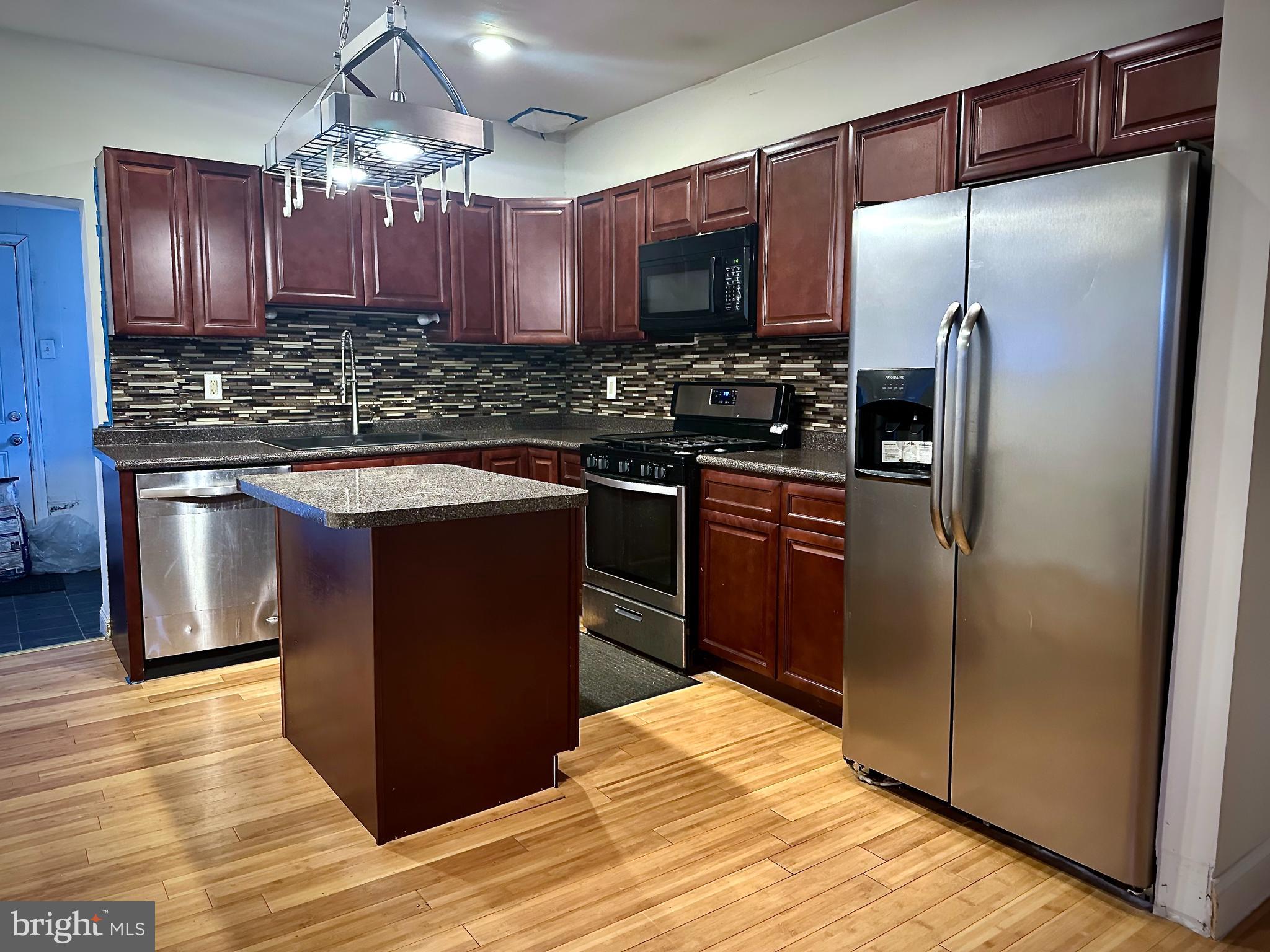 6209 Walnut Street Philadelphia, PA 19139 - Photo 5 of 13 a kitchen with kitchen island granite countertop wooden cabinets and stainless steel appliances