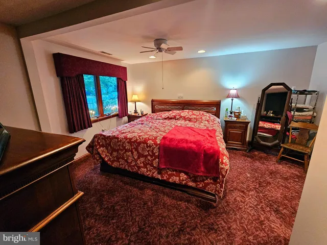 a bedroom with a bed a dresser and windows