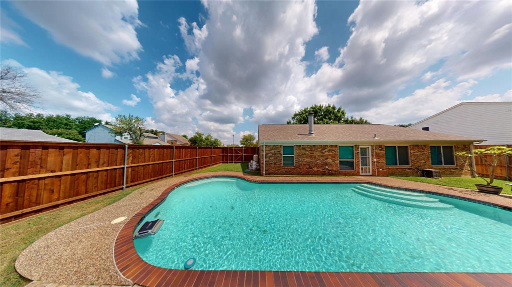1317 Colonial Place Flower Mound, TX 75028 - Photo 17 of 20 Backyard oasis featuring an in-ground swimming pool with integrated steps, surrounded by a combination of wood-finish decking and exposed aggregate concrete