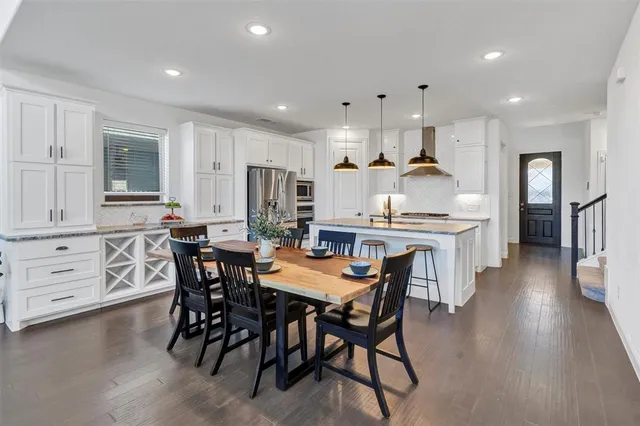 a kitchen with stainless steel appliances kitchen island granite countertop a table chairs stove and white cabinets