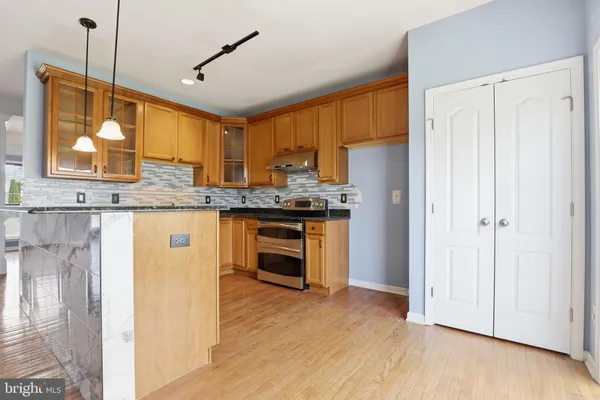 a kitchen with stainless steel appliances granite countertop a stove a sink and a refrigerator with wooden floor