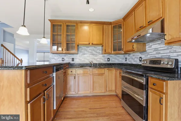 a kitchen with stainless steel appliances granite countertop a sink and a stove