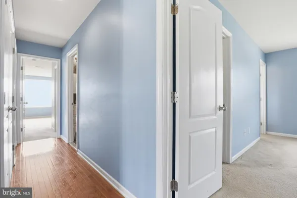 a view of a hallway with wooden floor and a bathroom