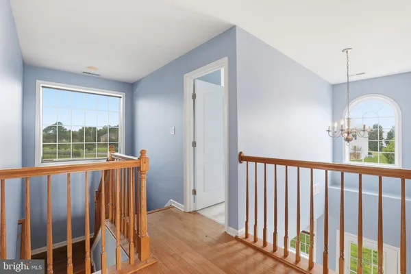a view of a hallway with wooden floor and windows