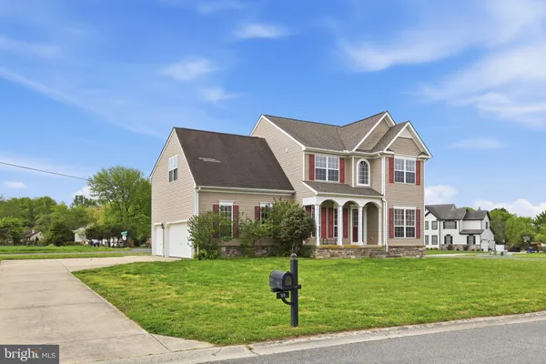 a front view of a house with a garden and trees